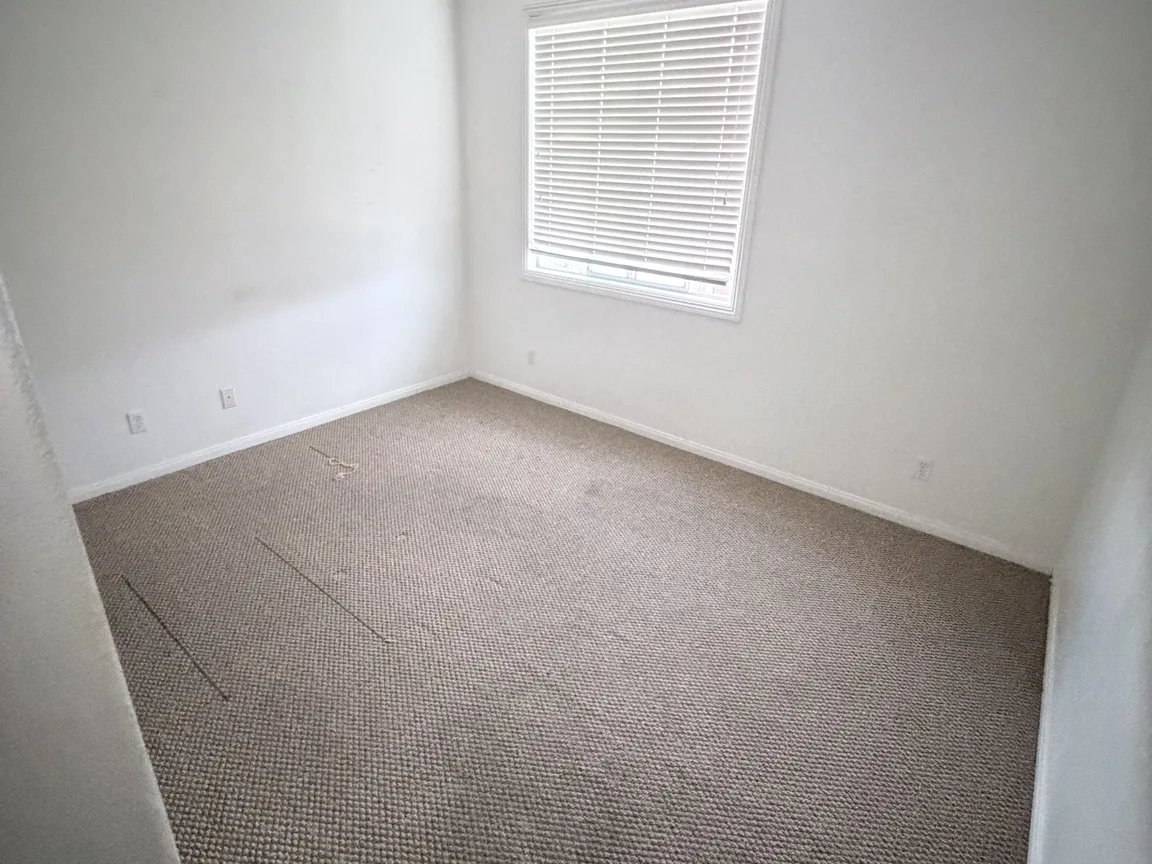 Before: empty bedroom with window and carpet